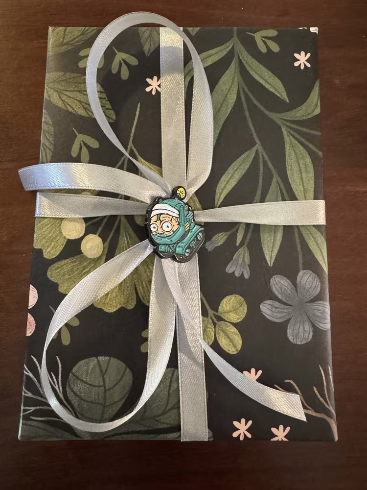 A wrapped gift with a Project Blue enamel pin in the bow